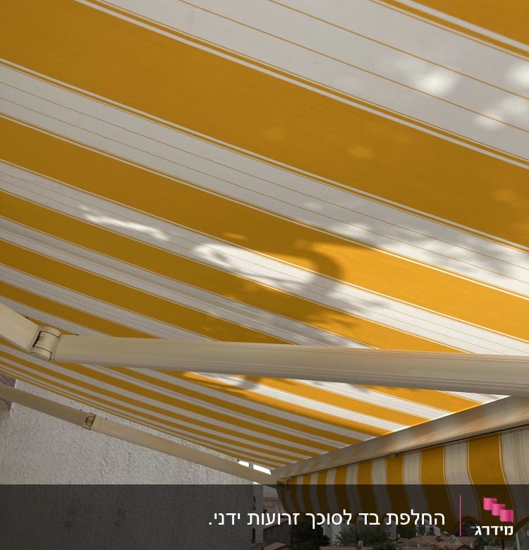 סוכך פסים צהוב ולבן על מרפסת